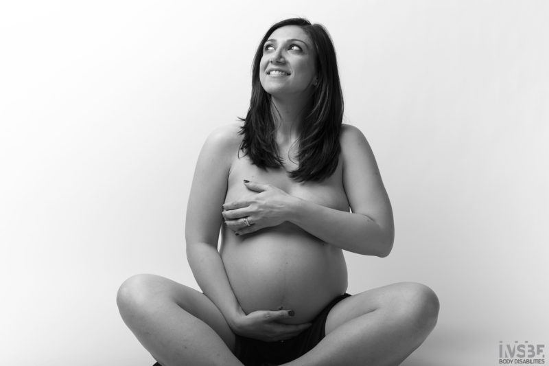 Donna con il pancione seduta a gambe incrociate